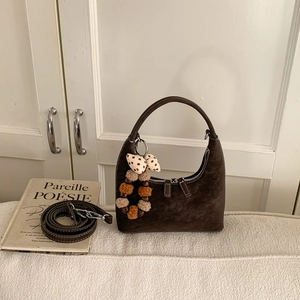 Detail of coffee brown suede dumpling bag with vintage pompom and adjustable strap