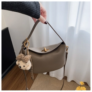 Detail of greyish-brown lychee grain leather handbag with plush bear charm and lock