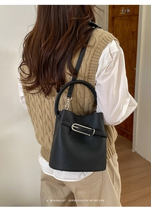 Détail d'un sac seau en cuir grainé noir porté en bandoulière, vue arrière sur modèle