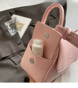 Detail of pink lychee leather handbag featuring side pocket and silver magnetic clasp