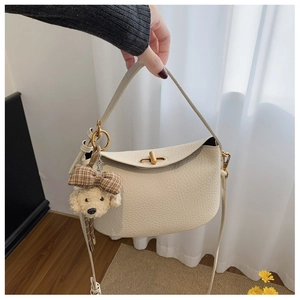 Detail of cream white leather hobo bag with gold turn-lock and cute dog charm pendant