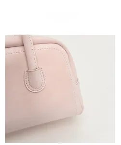 Close-up of pink leather baguette bag showing reinforced stitching and handle connection
