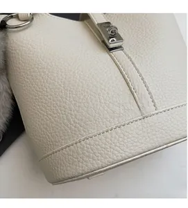 Detalle del bolso de cuero blanco roto con textura de lichi y hebilla de metal plateado