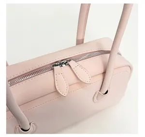 Close-up of pink leather handbag showing smooth silver dual metal zippers and fine stitching