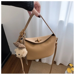 Detail of lychee pattern leather handbag with gold twist lock and cute plush bear charm