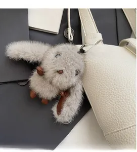 Primer plano de un colgante de conejo gris esponjoso en un bolso de cuero blanco elegante