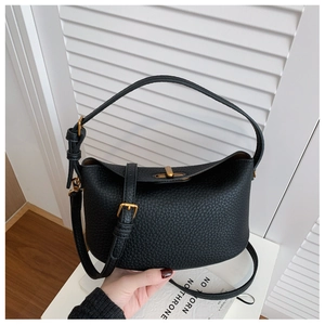Detail of black lychee grain leather bucket bag with gold hardware and top handle