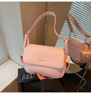 Detail view of pink pebbled leather crossbody bag with flap and side pocket design
