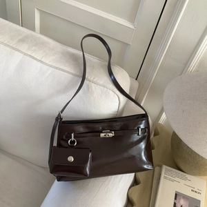 Dettaglio borsa a spalla marrone lucido con fibbia d'argento e piccola pochette