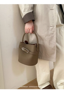 Gros plan d'un sac seau marron en cuir grainé lychee avec détails de boucles argentées
