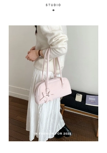 Detail of a light pink baguette shoulder bag with star charm in a minimalist studio setting