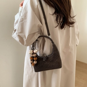 Detail view of coffee hobo bag with contrast stitching and decorative plush pendant