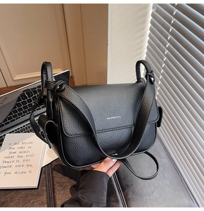 Detail of black lychee grain leather handbag with silver logo and knotted shoulder strap