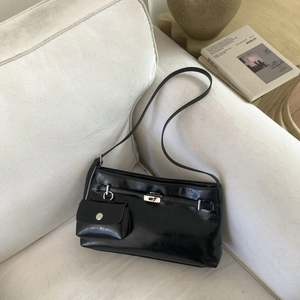 Dettaglio della borsa a spalla in pelle lucida nera con fibbia e mini pochette