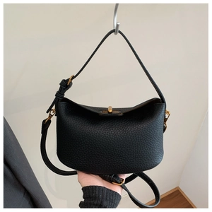 Detail of black lychee grain leather bag with gold buckle and adjustable strap