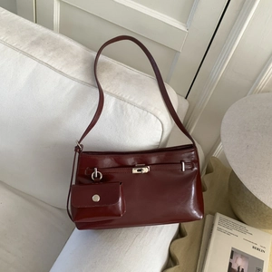 Dettaglio della borsa a tracolla in pelle bordeaux con chiusura d'argento e pochette