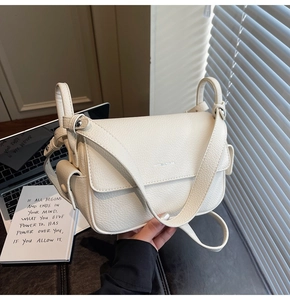 Close-up of beige lychee grain leather handbag with silver logo and wide shoulder strap