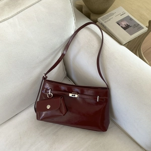 Dettaglio borsa sottobraccio in pelle lucida bordeaux con fibbia e mini portamonete