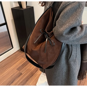 Détail d'un grand sac bandoulière en daim marron avec de larges bretelles noires