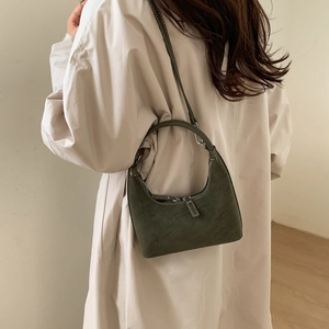 Close-up of olive green suede crescent bag featuring white contrast stitching and dual zippers
