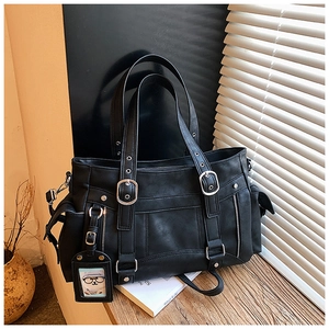 Dettaglio della borsa tote nera con fibbie in metallo e decorazioni in pelle su legno