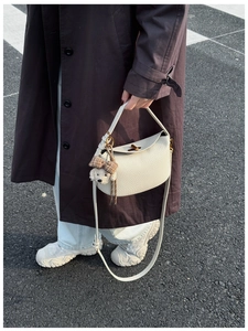Detail view of cream lychee pattern leather handbag with cute dog charm on street