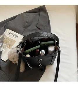 Dettaglio borsa a secchiello in pelle nera martellata con chiusura metallica e ciondolo