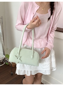 Detail of mint green PU baguette bag with star charm worn by model in casual style