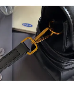 Détail rapproché du crochet en métal doré et de la bandoulière en cuir du sac noir