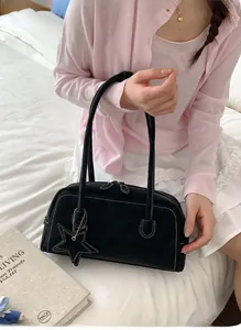 Detail of black suede Boston bag with white stitching and star charm in a lifestyle setting