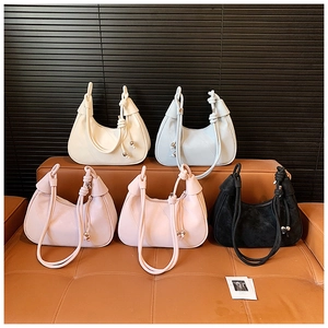 Detail of five crescent hobo bags in assorted colors with twisted rope straps and metal charms