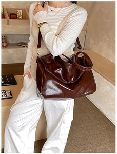 Borsa tote marrone lucida indossata da una modella in un interno moderno