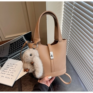 Detalle de bolso bucket de cuero camel con hebilla plateada y colgante de conejo de peluche