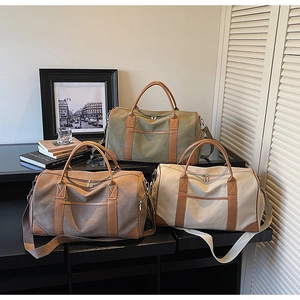 Three travel bags in olive, tan and cream canvas with leather trim on a display shelf