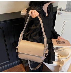 Close-up of litchi texture on beige leather crossbody bag with adjustable wide shoulder strap
