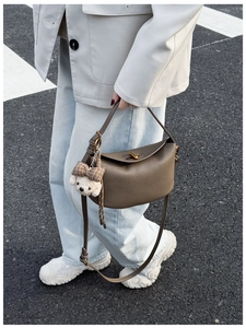 Close-up of dark brown lychee texture leather bag with matte gold knob and bear charm
