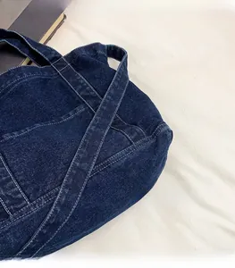 Close-up of dark blue denim tote bag featuring white contrast stitching and soft fabric texture