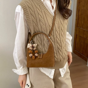 Brown faux suede dumpling bag with crescent design and decorative bow charm