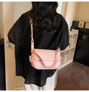 Close-up of pink litchi grain leather crossbody bag worn by model in a cozy room