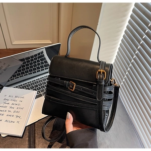 Détail d'un sac à main en cuir noir avec boucles dorées vintage et silhouette carrée chic