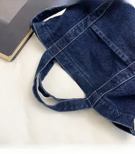 Close-up of indigo denim tote bag handles showing detailed contrast stitching craft