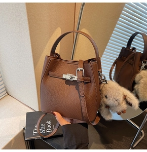 Dettaglio di una borsa a secchiello marrone con trama litchi e fibbia argentata