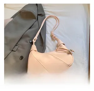 Detail of pink crescent bag featuring geometric stitching and knotted strap with gold beads