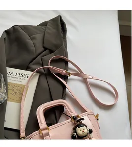Détail du sac seau rose avec boucle dorée, bandoulière et breloque de fille mignonne
