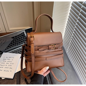 Détails d'un sac en cuir marron avec sangles décoratives et boucles métalliques dorées