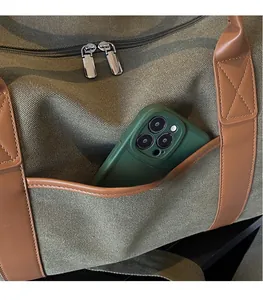 Detail of olive canvas travel bag with brown leather trim and side pocket for phone