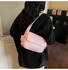 Detail of pink textured leather shoulder bag showing the strap and small hanging accessory