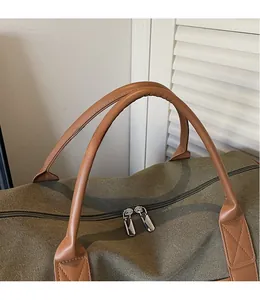 Close-up of durable olive canvas travel bag featuring brown leather handles and metal zipper