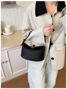 Detail of black lychee grain leather handbag with gold hardware in a home setting