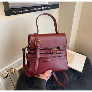 Gros plan détaillé du sac à main en cuir rouge foncé avec boucles dorées style rétro
